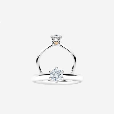 © Juwelier Wagner-Madler e.K. Ein funkelnder Solitär-Diamant-Verlobungsring mit einem eleganten Band aus Weißgold. Der Diamant wird von vier Zinken gehalten und ist elegant auf einem schmalen Band zu sehen. Dieses Schmucklexikon-Juwel verfügt über eine minimalistische Fassung, die die Brillanz des Edelsteins vor einem schlichten, hellen Hintergrund hervorhebt.
