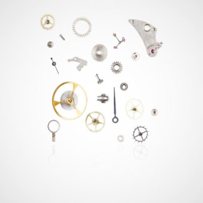 Eine Sammlung verschiedener Uhrenkomponenten, darunter Zahnräder, Schrauben und eine Aufzugswelle, ist vor einem weißen Hintergrund angeordnet. Die Teile sind ausgebreitet und zeigen die komplizierten Elemente, aus denen der innere Mechanismus einer Uhr besteht. Es ähnelt einem zum Leben erweckten Uhrenlexikon.