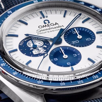 Nahaufnahme eines Zifferblatts der Omega Speedmaster Professional, das im Uhrenlexikon vorgestellt wurde und ein blau-weißes Design aufweist. Das Zifferblatt umfasst drei Hilfszifferblätter und eine Abbildung eines Astronauten im linken Hilfszifferblatt. Die Worte „ST3 ANNY VERSARY“ sind teilweise in der Nähe des Astronauten sichtbar.
