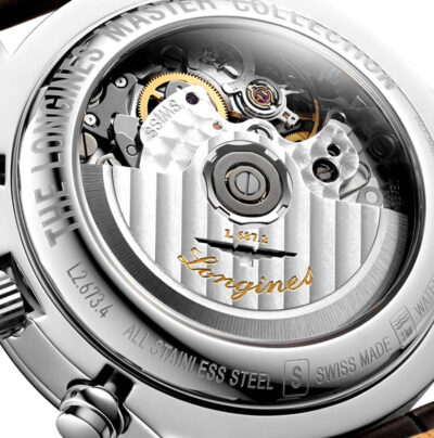 Nahaufnahme der Rückseite einer Luxusarmbanduhr, die ihr kompliziertes mechanisches Uhrwerk zeigt. Zu den Gravuren gehören „THE LONGINES MASTER COLLECTION“, „ALL STAINLESS STEEL“, „SWISS MADE“ und „WATER-“, zusammen mit dem Markennamen „Longines“, der in das Uhrwerk eingraviert ist. Eine kleine Krone ist sichtbar und verkörpert die Pracht des Uhrenlexikons.